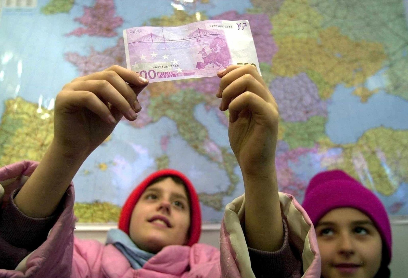 Twee kinderen houden een briefje van 500 euro in de lucht.