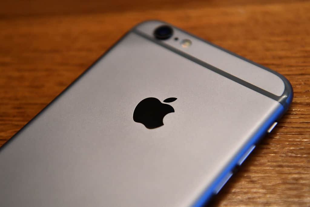 Een grijze iPhone ligt met zijn rug naar boven op een houten tafel.