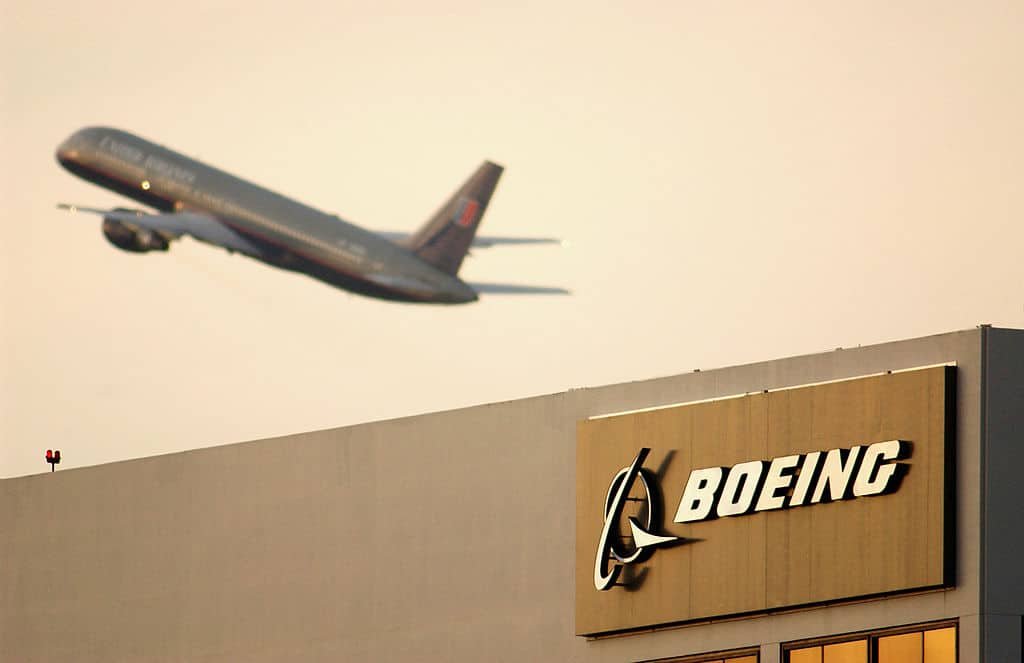 Een vliegtuig stijgt op boven het gebouwen met het logo van Boeing.