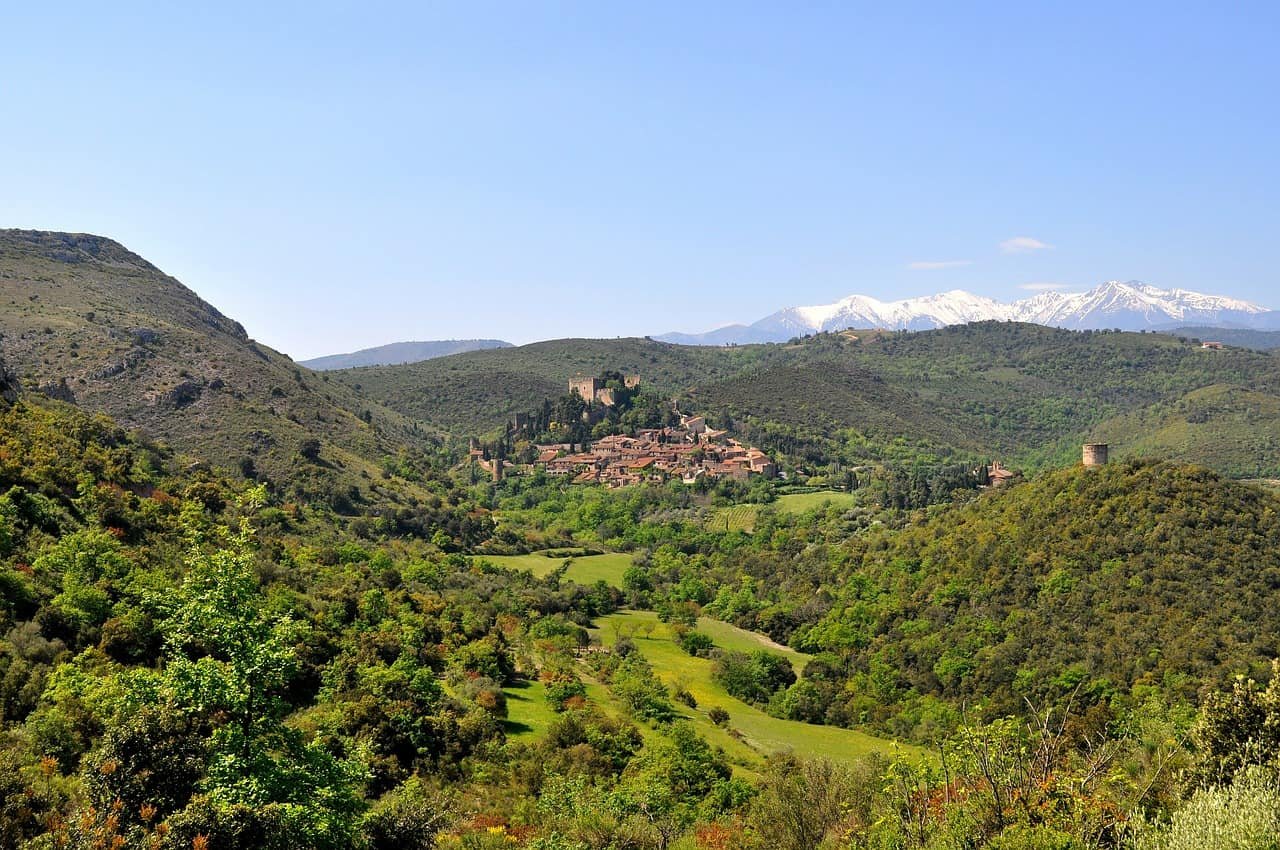 Een groen landschap met in de verte Castelnou, een van de mooiste Franse dorpjes.