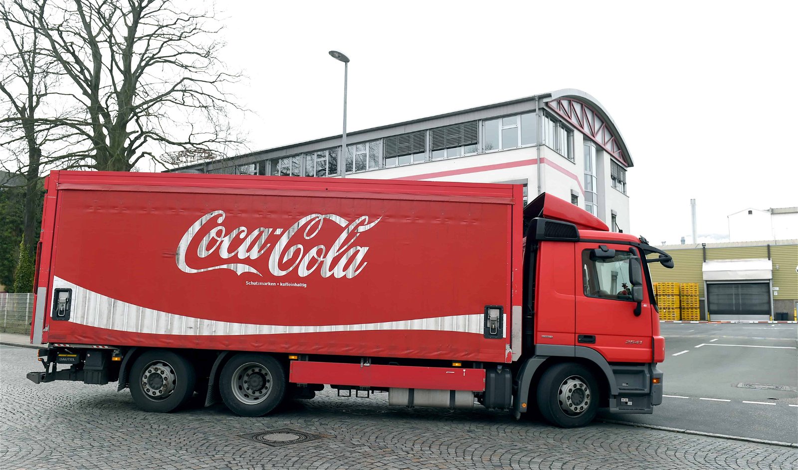 Een rode vrachtwagen van Coca-Cola rijdt over de baan.