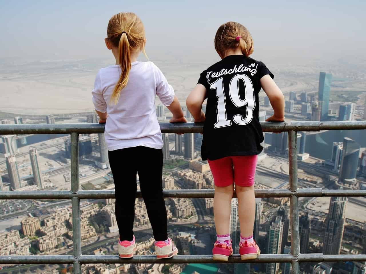Twee kindjes staan op een railing en kijken uit over Dubai.