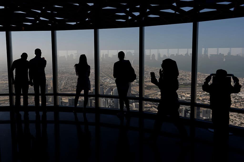 Mensen kijken vanuit een toren een raam uit over Dubai.