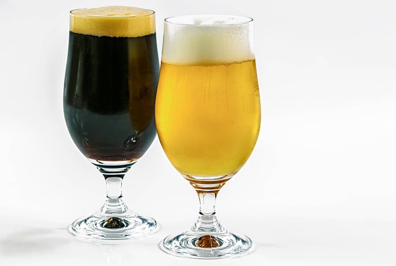 Un verre de bière brune à côté d'un verre de bière blonde.