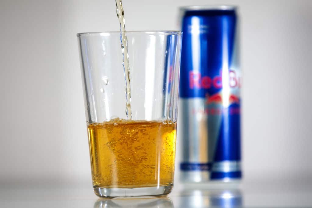 Een blikje Red Bull wordt leeggeschonken in een glas.