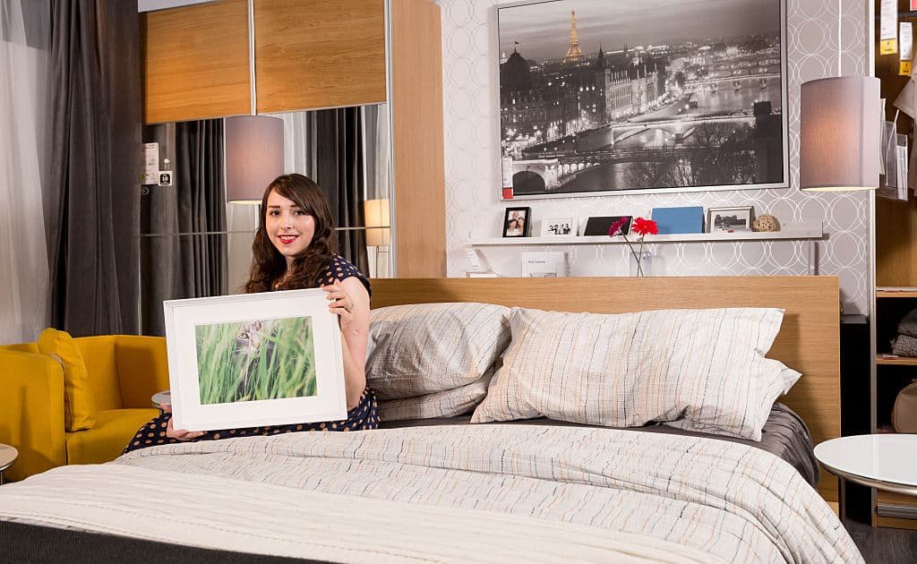 Een vrouw zit op een bed en houdt een foto in een kader vast.