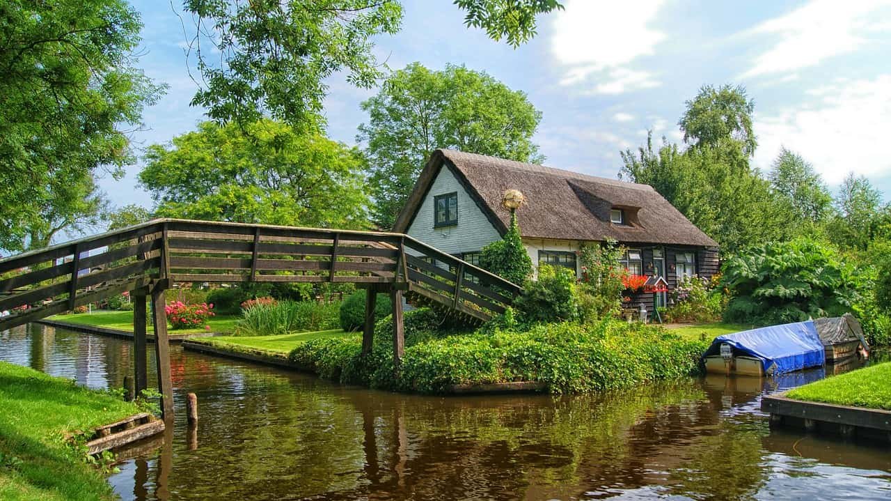 Een hout brug over een beekje leidt naar een wit huis in Giethoorn, een van de mooiste Nederlandse dorpjes.
