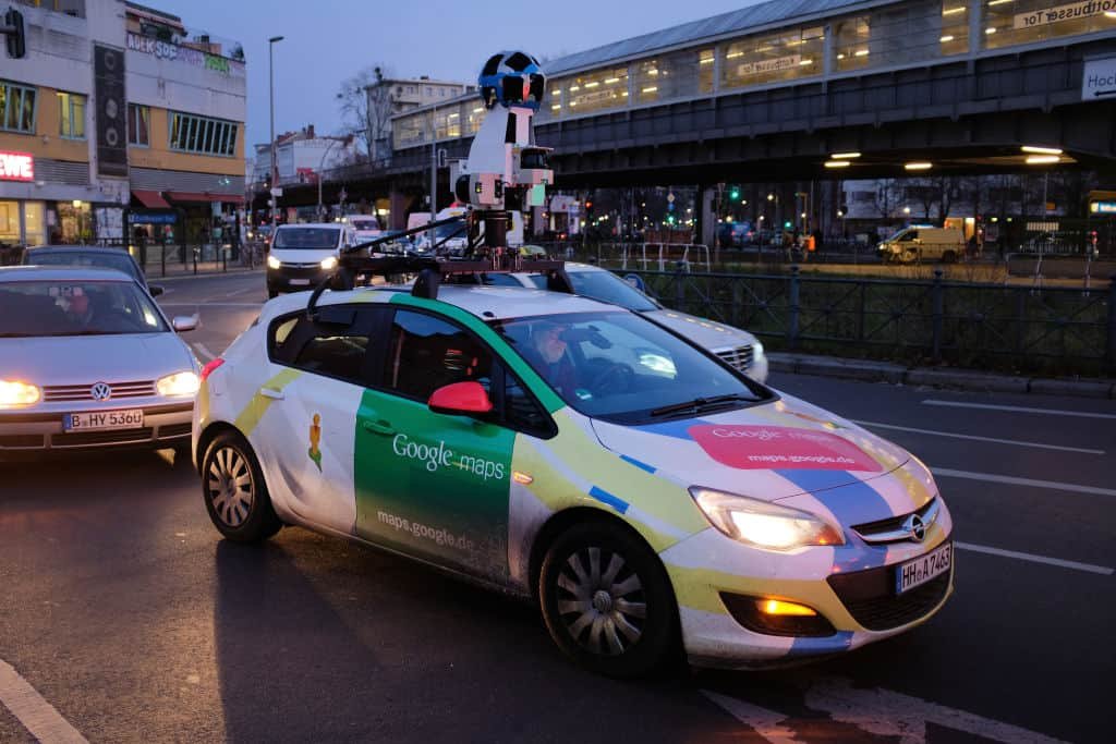 Een auto in verschillende kleuren rijdt met een opvallende camera op het dak. Google maakt op deze manier beelden voor Street View.