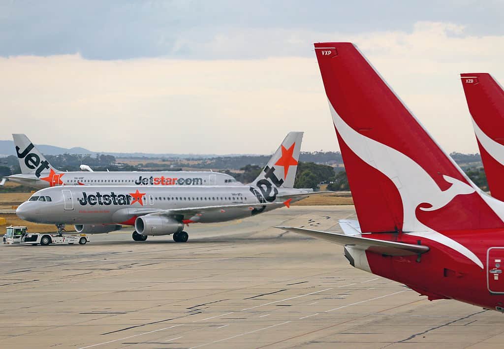 Een vliegtuig van low cost-maatschappij Jetstar staat tussen andere vliegtuigen.