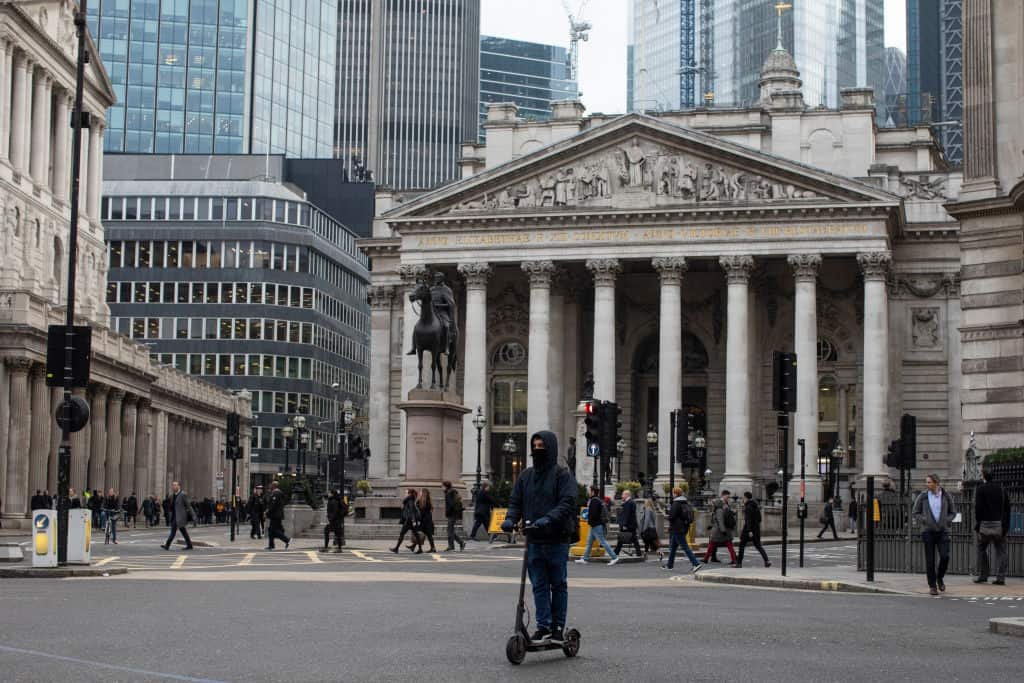 Man op elektrische scooter rijdt langs Bank of England.