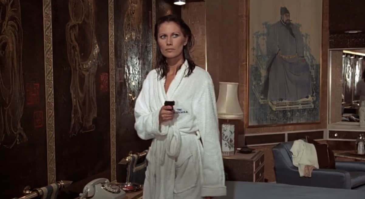 Actrice Maud Adams in een Bond-films in badjas terwijl ze een revolver vasthoudt.