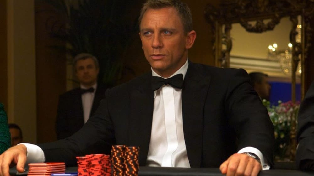 Daniel Craig zit als James Bond aan een pokertafel.