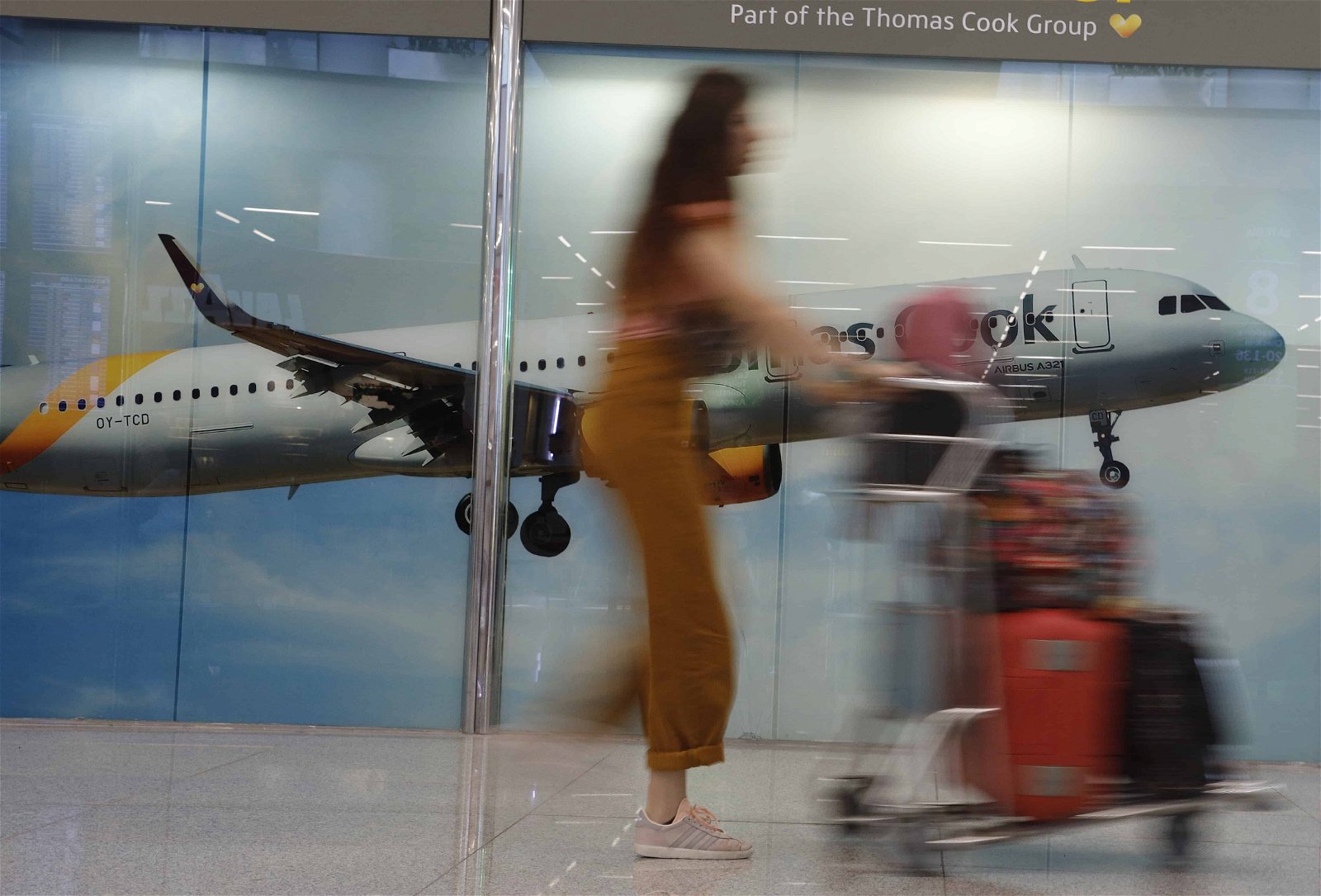 Een man in werkkledij staat aan de deur bij de staart van een vliegtuig van Thomas Cook.