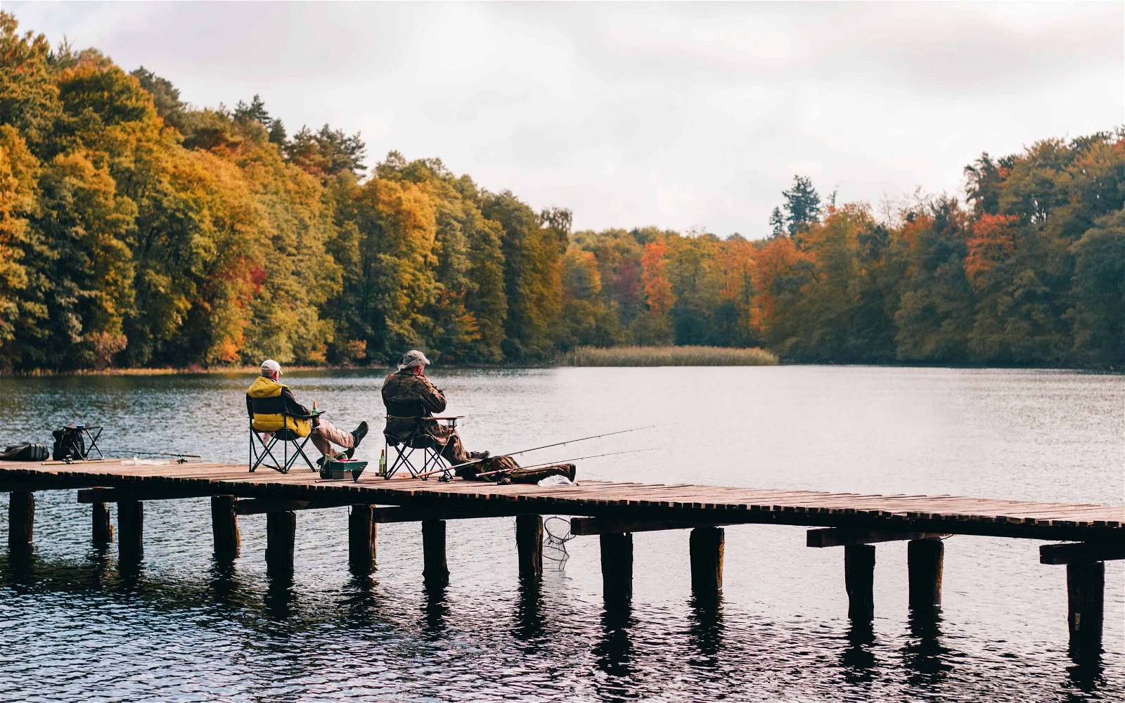 Twee mannen zitten vanaf de kade in een meer te vissen.