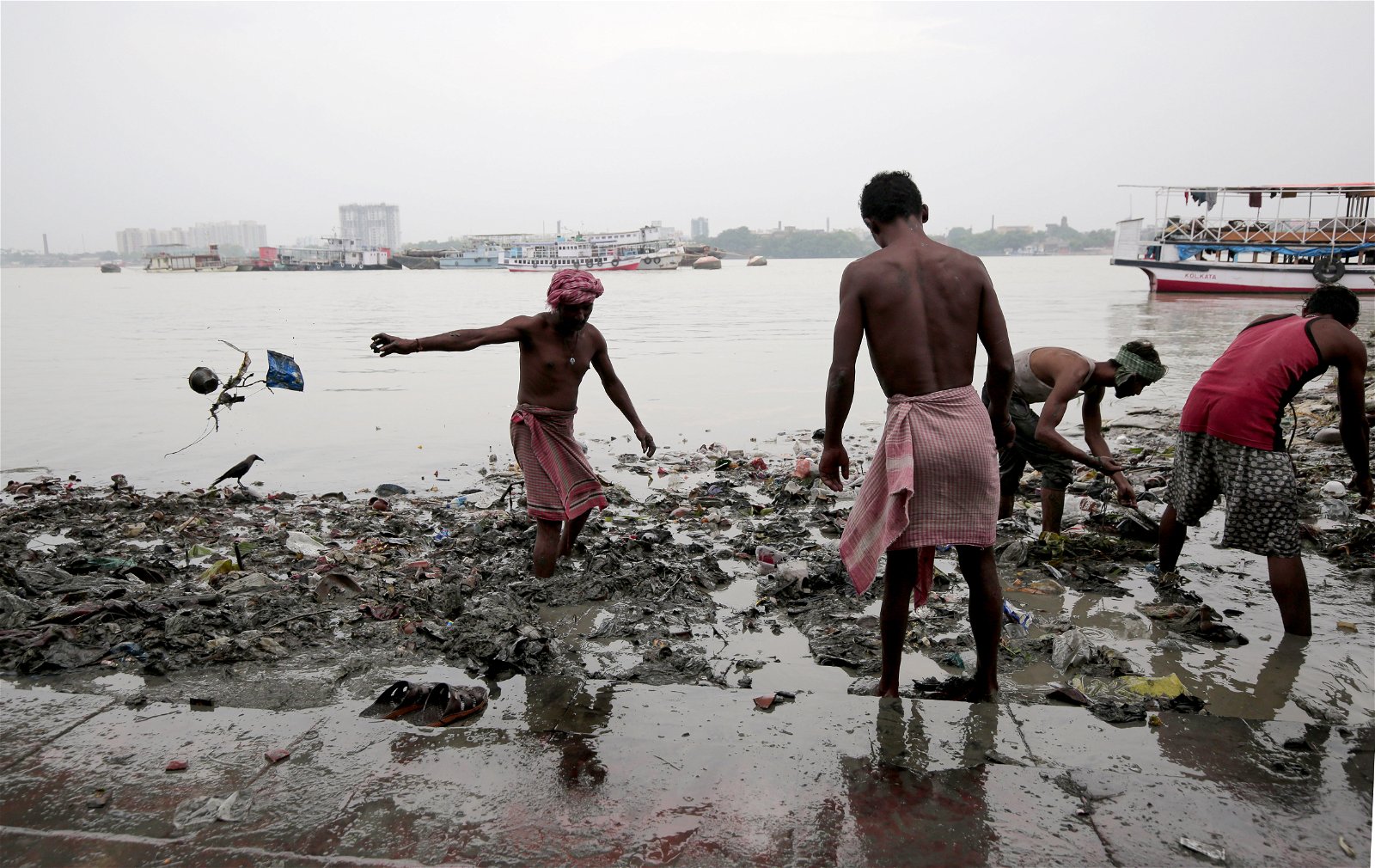 Mensen lopen door met plastic bezaaid water in India, een land waar de watercrisis ernstige gevolgen kent.