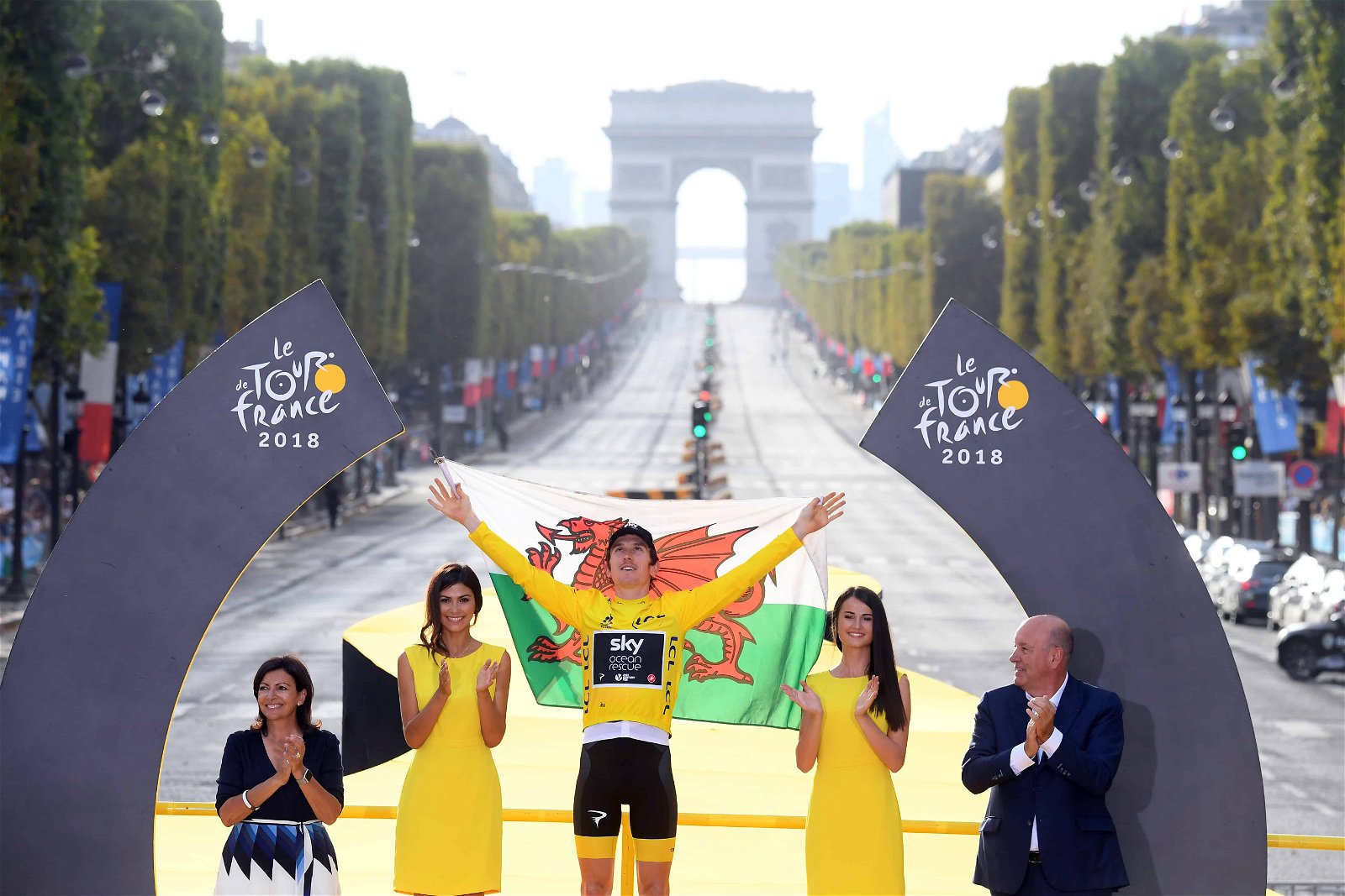 Geraint Thomas steekt de handen in de lucht op het podium als winnaar van de Tour de France.