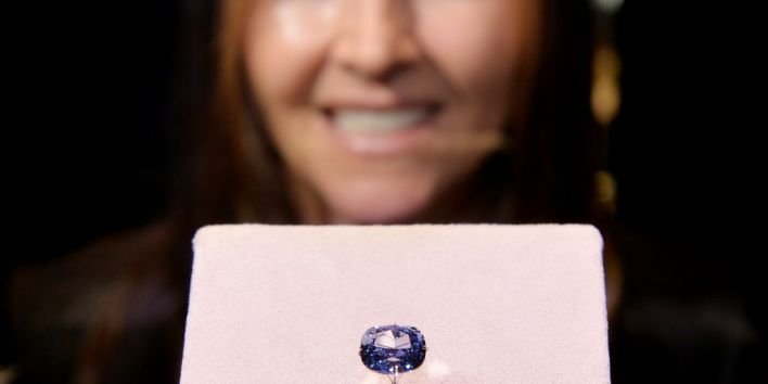 Suzette Gomes, CEO of Cora International, poses with the 12-carat "Blue Moon Diamond" which is on display at the Natural History Museum in Los Angeles on September 12, 2014. The 'Fancy Vivid Blue Diamond' which are extremely rare was discovered in South Africa. AFP PHOTO/Mark RALSTON / AFP PHOTO / MARK RALSTON
