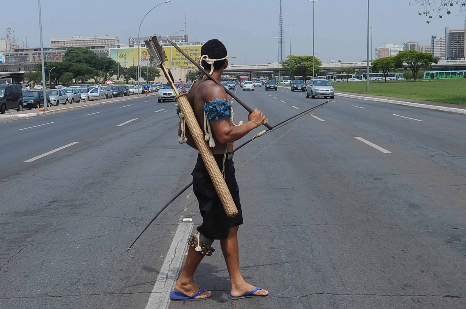 Een man uit een Braziliaanse stam steekt jachtmateriaal een snelweg over.