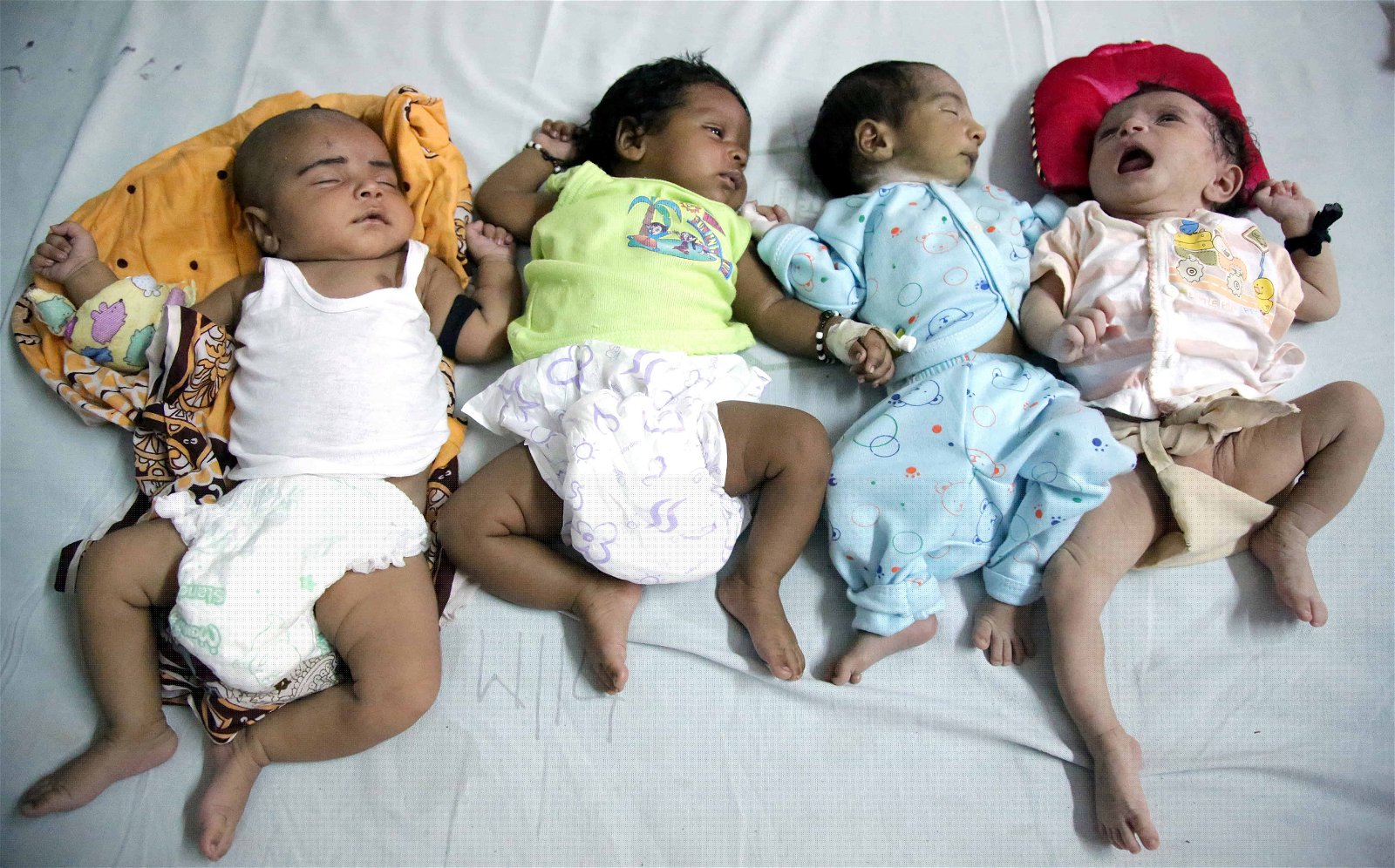 Vier baby's liggen op een rij naast elkaar in India.