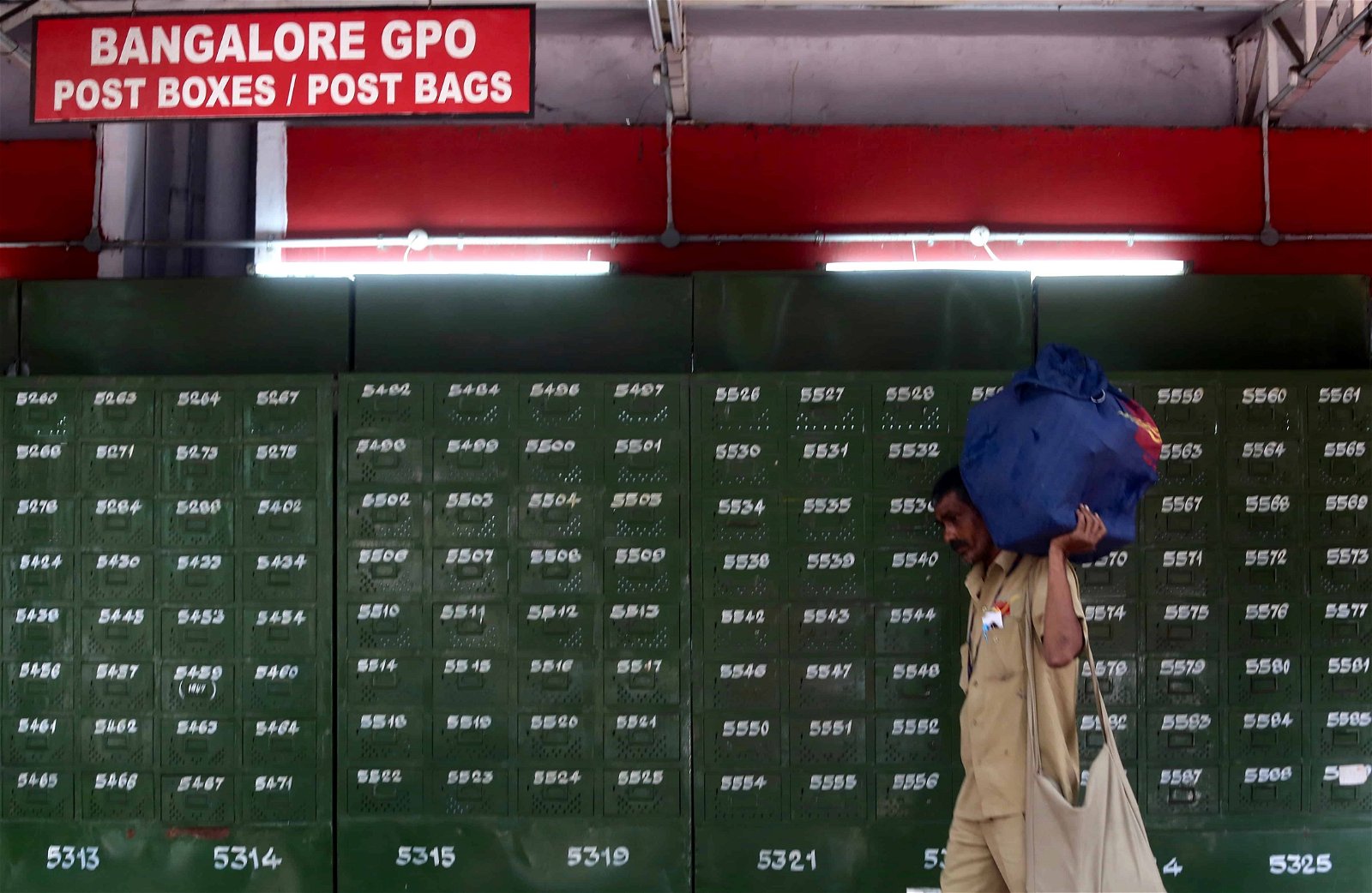 Een man loopt met een zak langs brievenbussen van een postkantoor in India.