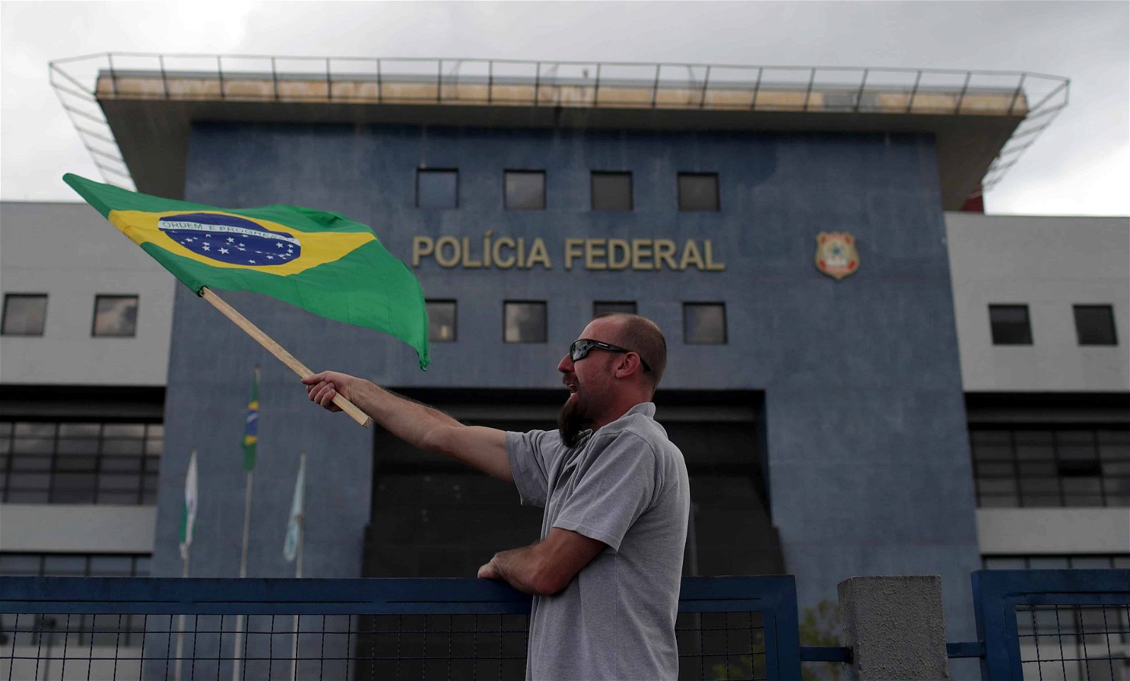 Een man loopt met een vlag van Brazilië langs het kantoor van de federale politie.