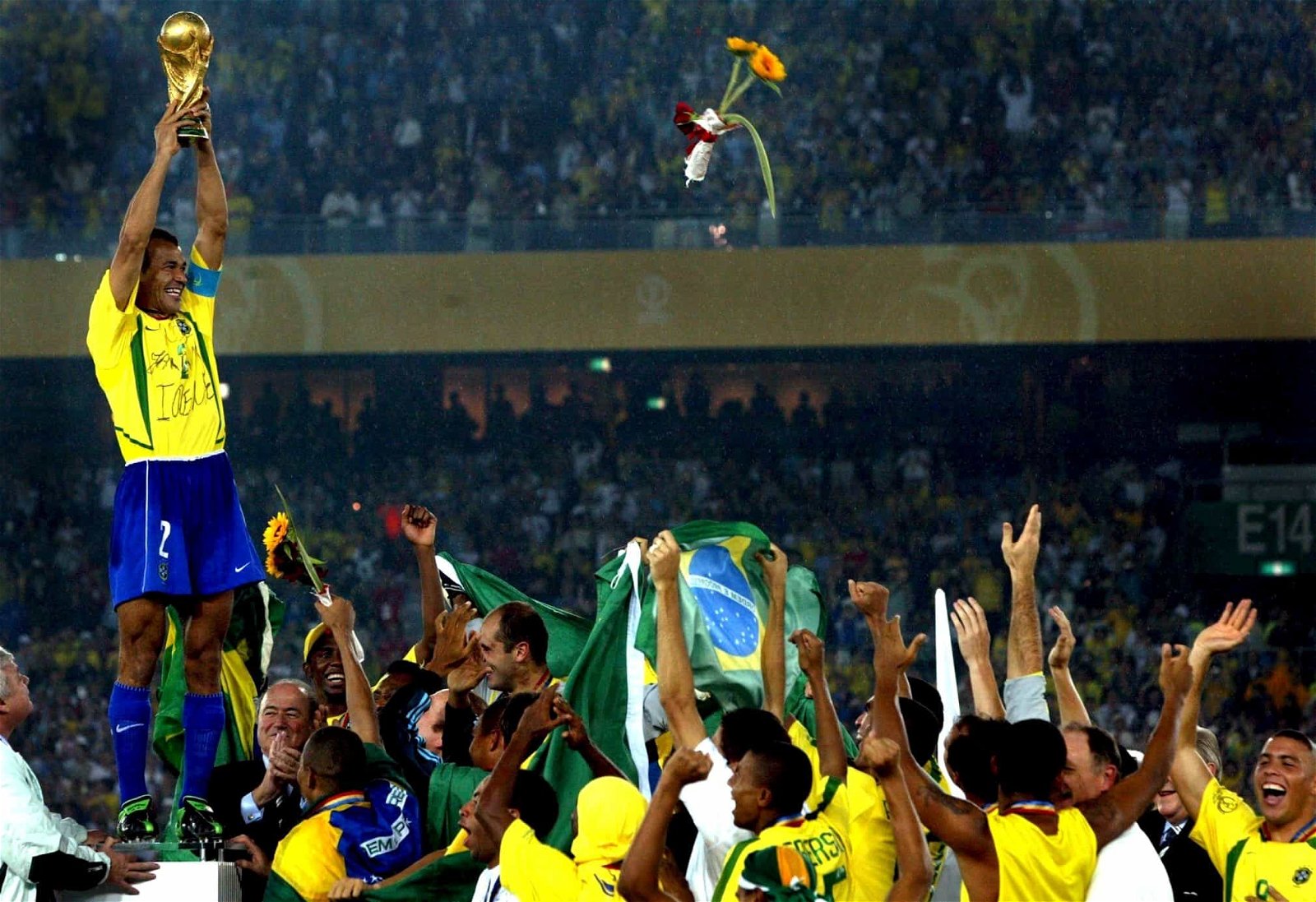 Een Braziliaanse voetballer houdt de wereldbeker omhoog terwijl zijn ploegmaats toekijken.