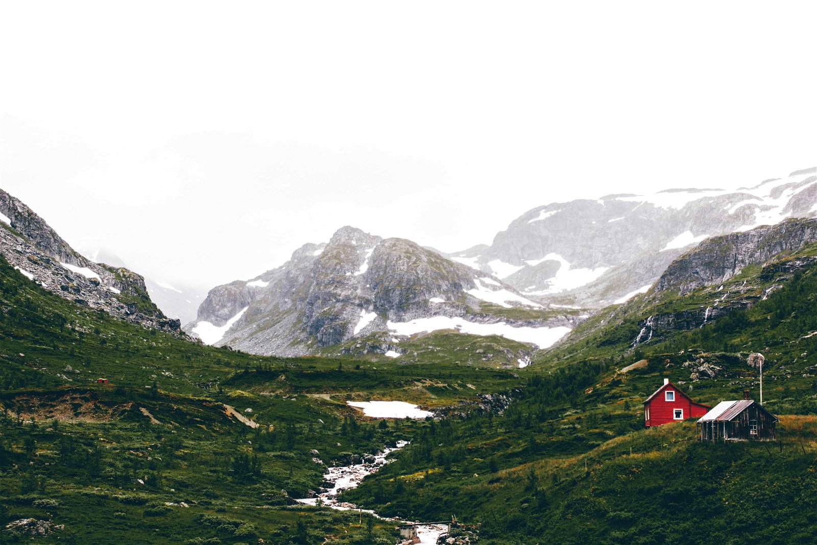 Een rood huisje met op de achtergrond een gletsjer in het Noorse Flam.