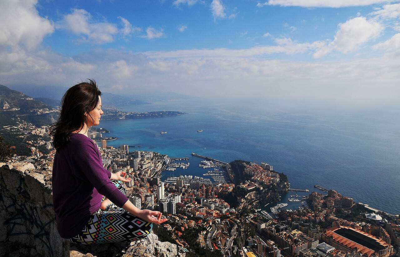 Une femme médite avec vue sur Monaco.