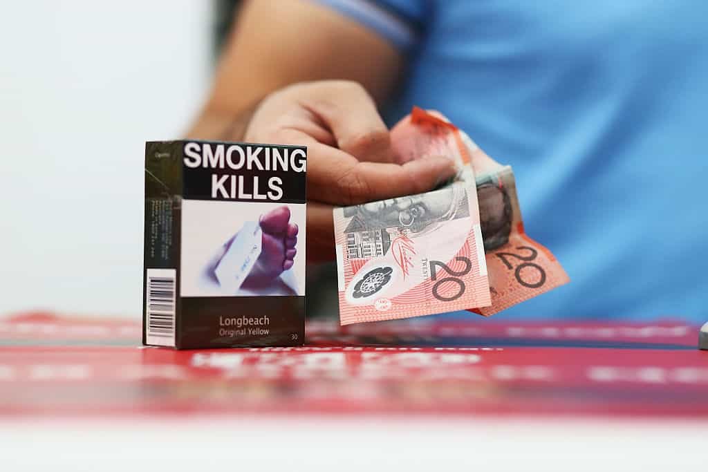 Een pakje sigaretten met de tekst 'roken doodt' op de toonbank, naast twee briefjes van 20 dollar.